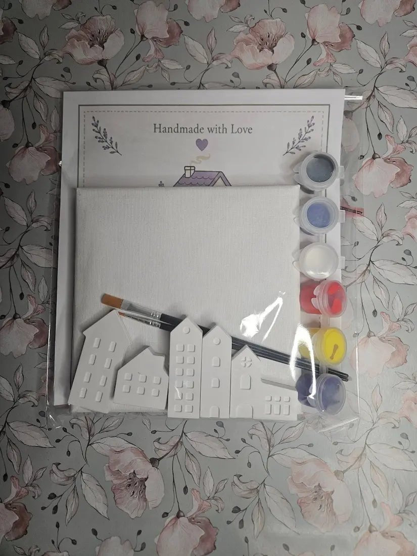 Set of white house-shaped moulds with paint and brush on a floral background